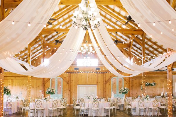 The interior of Shadow Creek barn in Virginia set up for a wedding reception with tables and flowing white cloth hanging from the ceiling