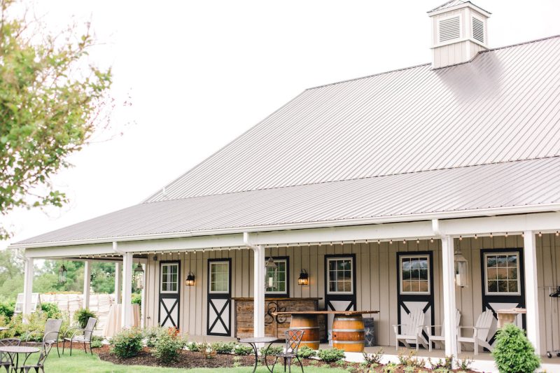 The exterior of Shadow Creek wedding venue in Virginia with a metal roof and rustic outdoor furniture under the overhang